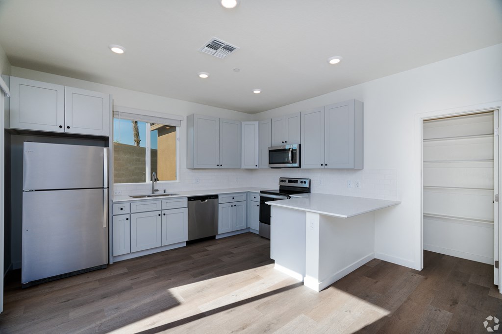 a kitchen with gray cabinets and stainless steel appliances